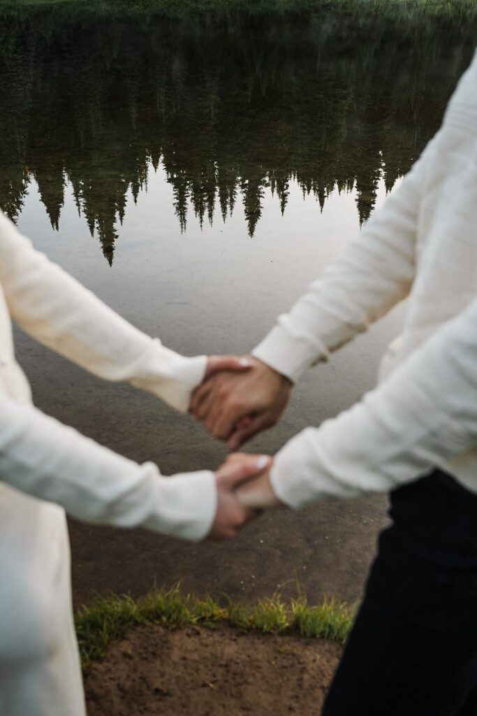 Bride and groom hold hands by an alpine lake during their sunrise elopement photos 