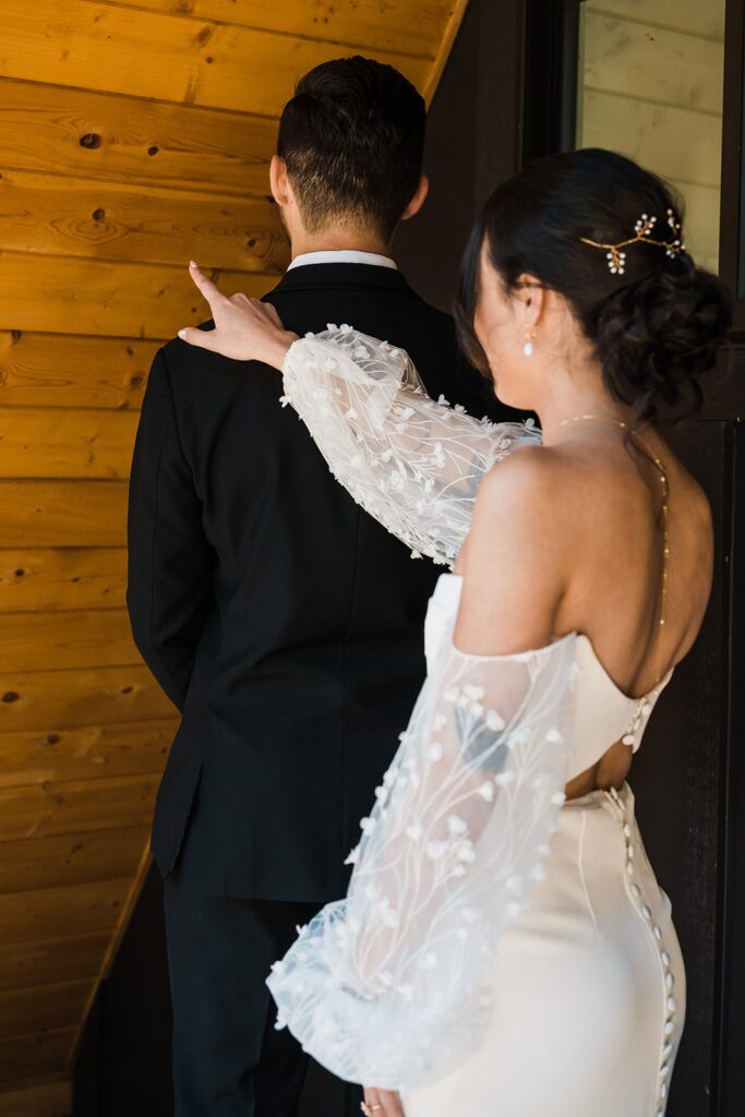 Bride taps groom on the shoulder for their wedding first look at their Airbnb cabin