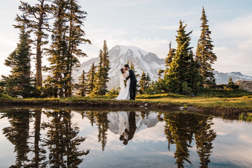 Bride and groom kiss by an alpine lake at their elopement at Mt Rainier National Park