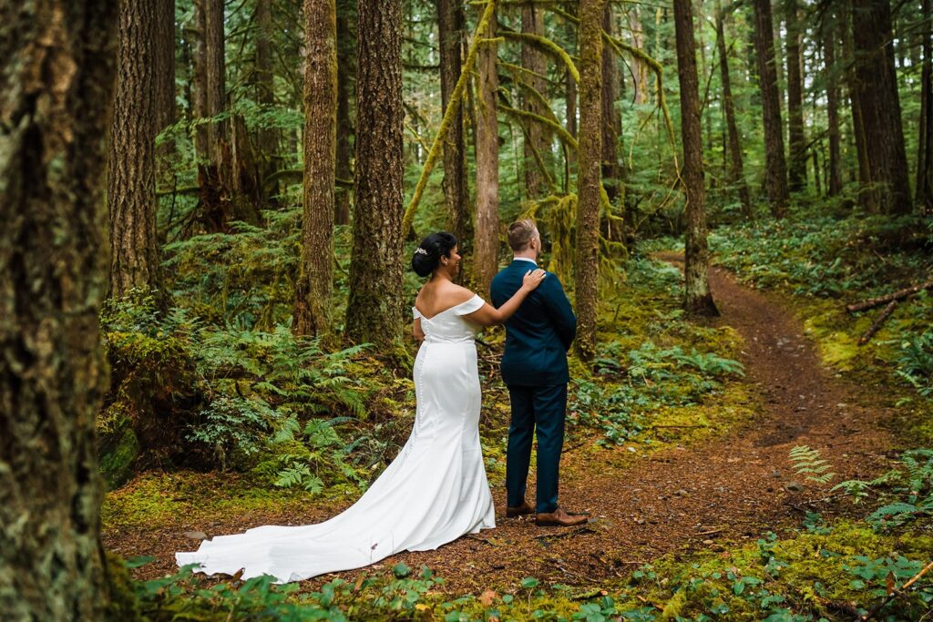 Bride taps groom on the shoulder for their first look in the forest in the North Cascades