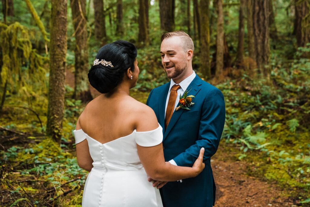 Bride and groom smile during their first look in the forest at their North Cascades elopement