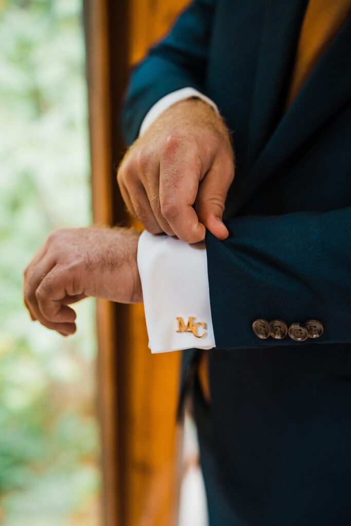 Groom adjusts custom gold cufflinks while getting ready for his elopement in the North Cascades