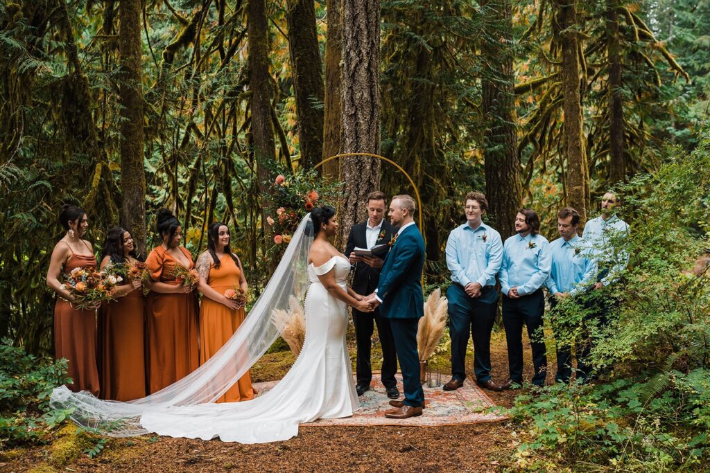 Bride and groom hold hands at the wedding altar during their family elopement in the forest 