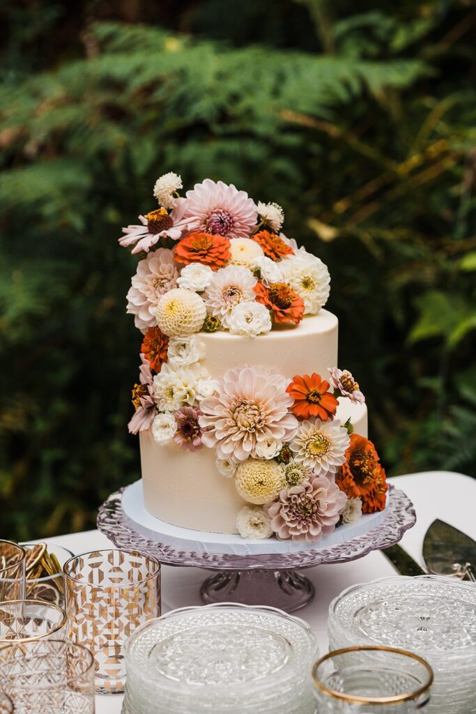 White two tier wedding cake with pastel and orange flowers