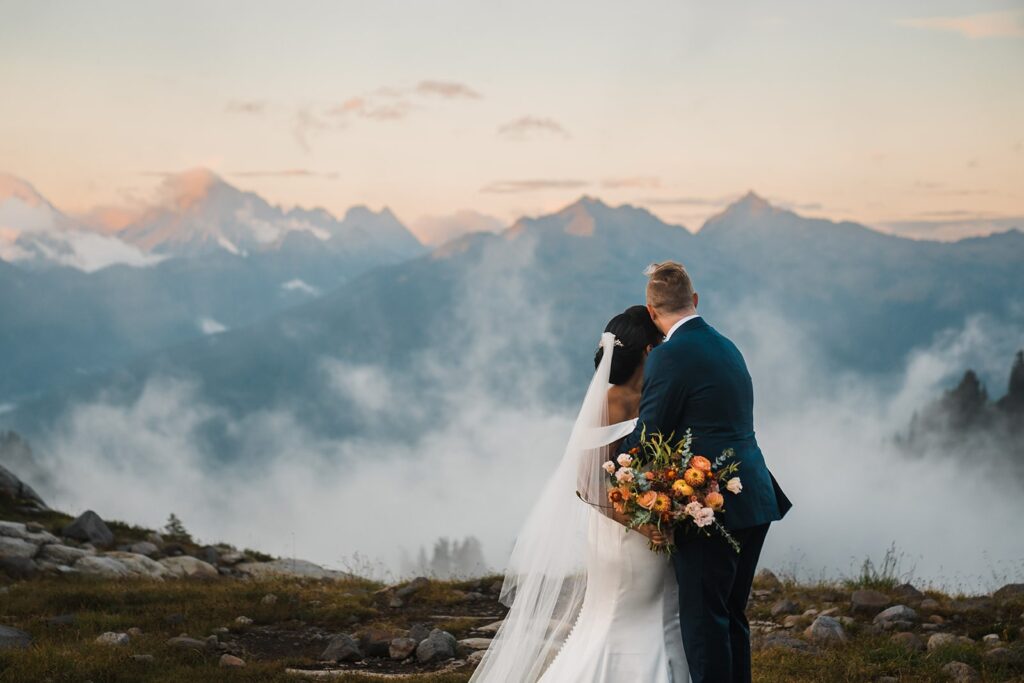 Bride and groom look out over the mountains during their sunset elopement photos in the North Cascades