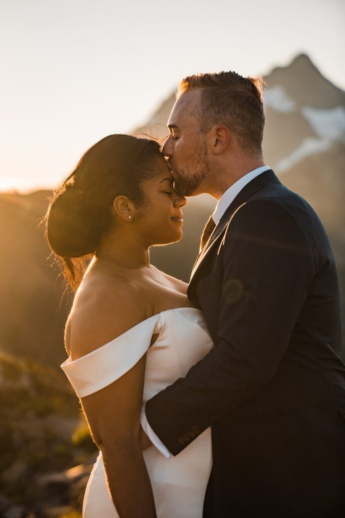 Groom kisses bride on the forehead during sunrise elopement photos at Artist Point