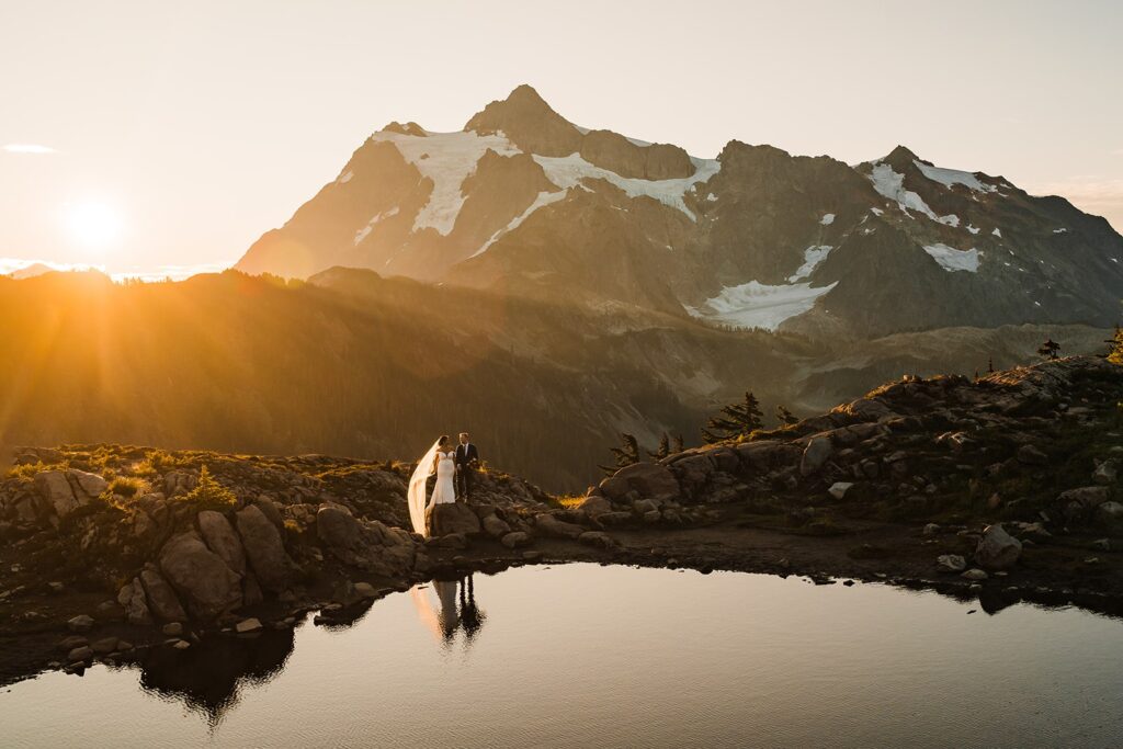Bride and groom stand next to an alpine lake during their sunrise elopement photos at Artist Point