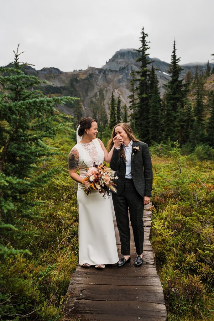 Bride kisses the other bride's hand during their wedding in the North Cascades