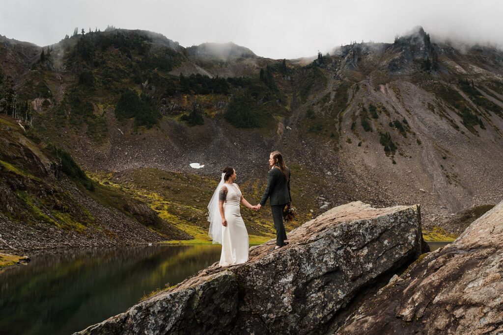 Brides hold hands while hiking during their North Cascades wedding 