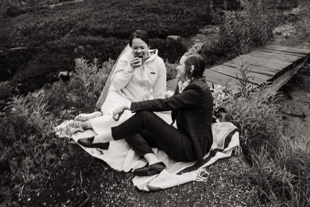 Brides laugh while sipping hot chocolate on a blanket in the North Cascades