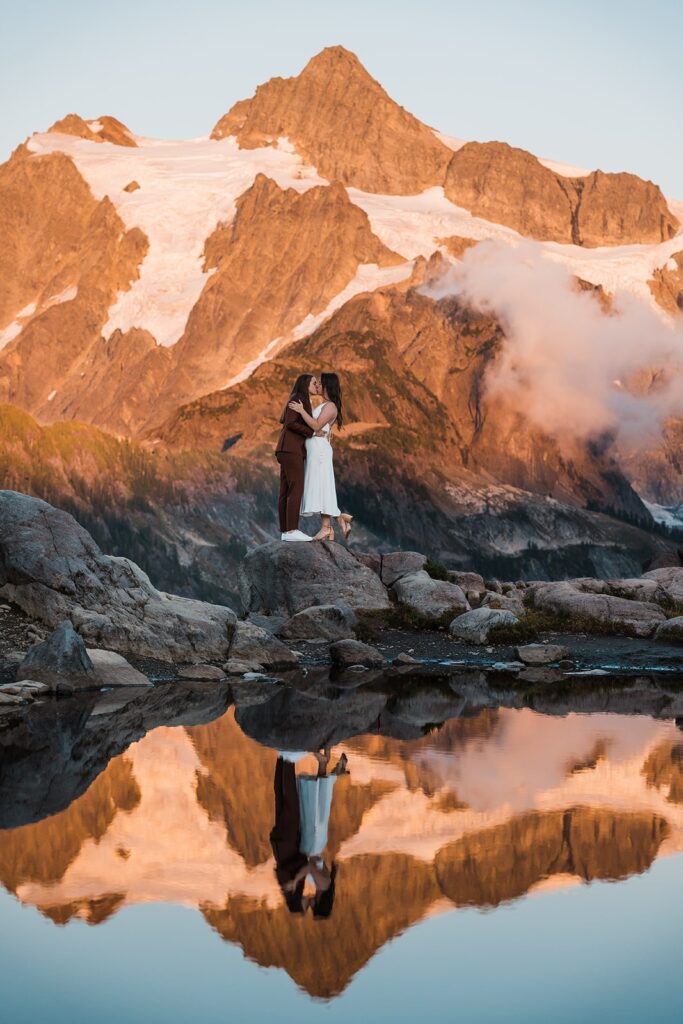 Brides kiss in front of an alpine lake in the North Cascades