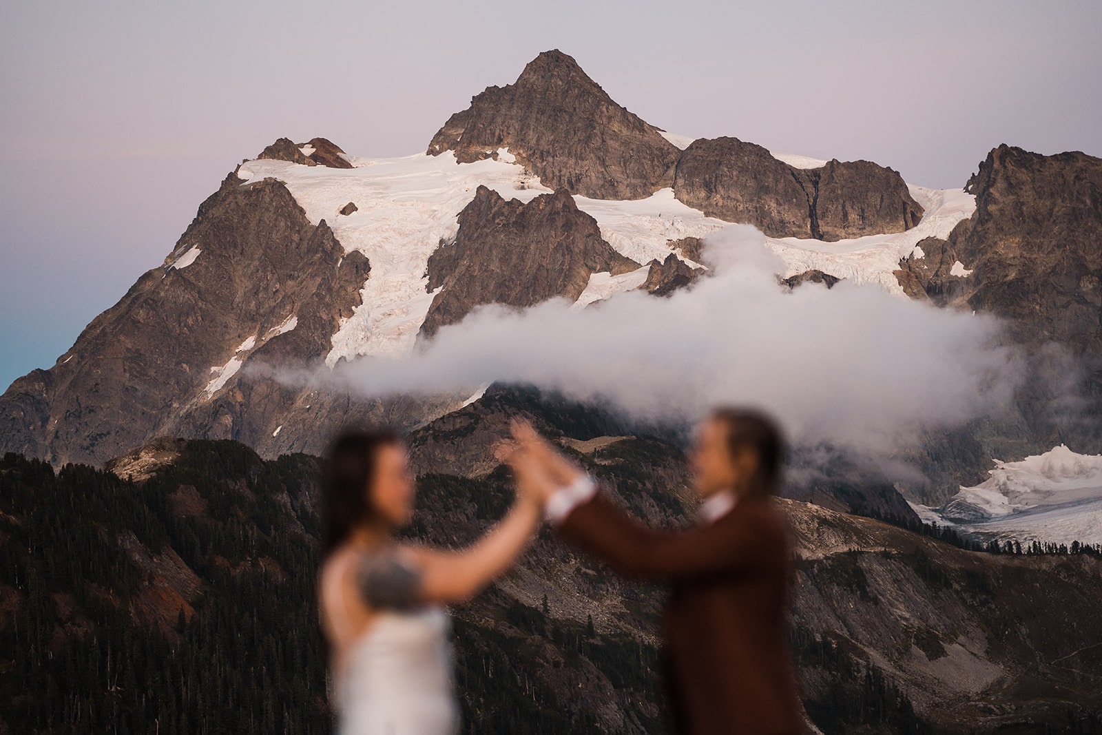 Brides touch hands while they elope in the Washington mountains