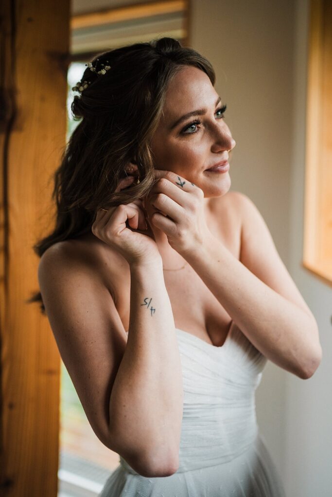Bride puts in earrings while getting ready for her forest elopement in Washington