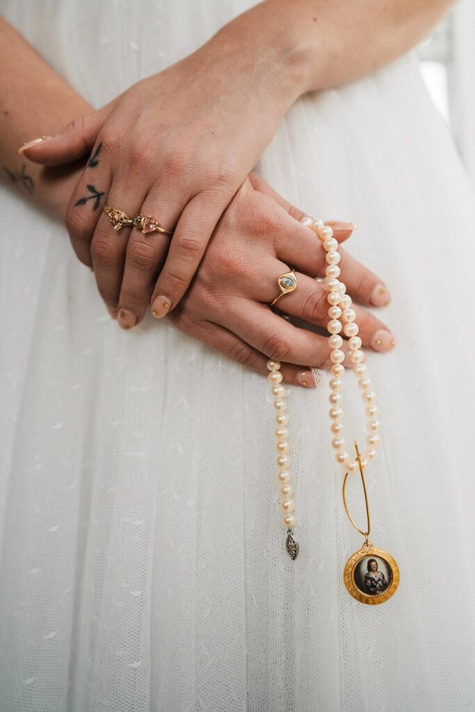 Bride holding strand of pearls with charm