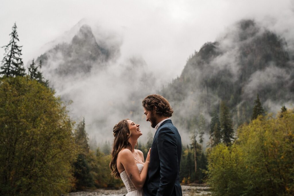 Bride and groom laugh during their rainy forest elopement in Snoqualmie