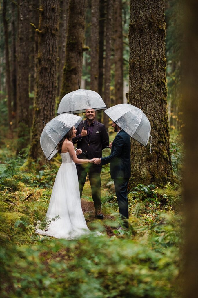 Bride and groom hold hands during their forest elopement ceremony