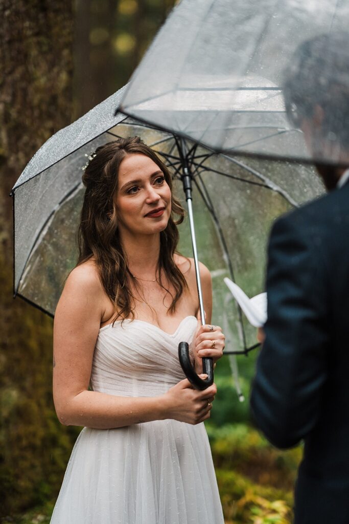 Bride gets emotional while groom reads vows during their forest elopement ceremony