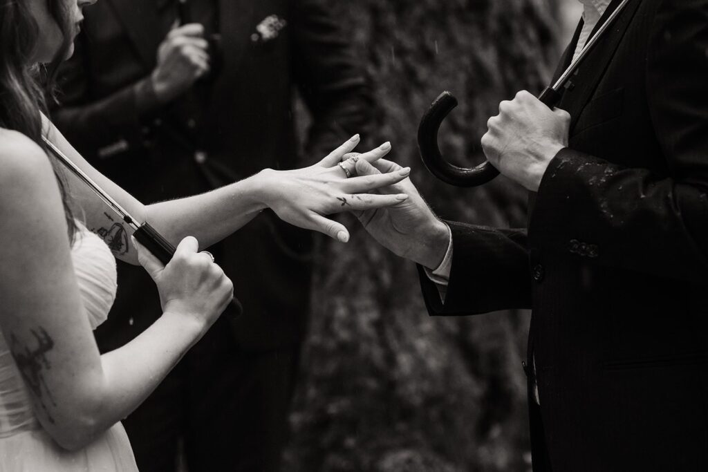 Groom puts ring on bride's finder during their forest elopement ceremony