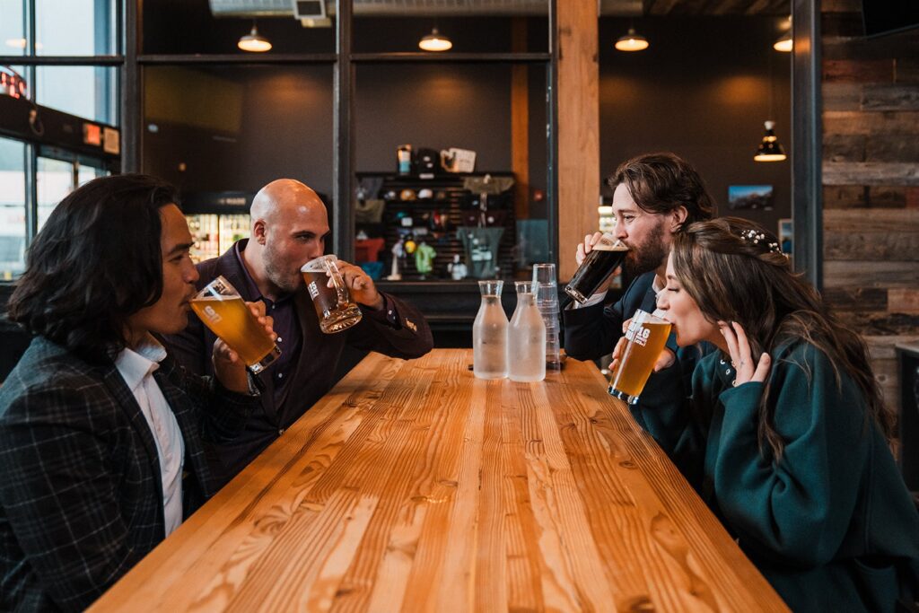 Bride and groom drink beers at a local brewery after their forest elopement