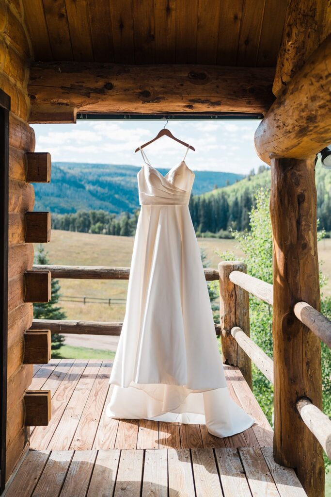 White wedding dress hanging from a cabin porch rafter