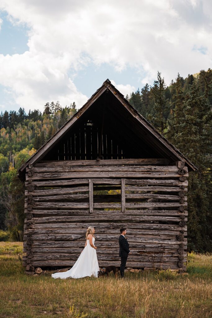 Bride and groom first look in front of a wood barn in Telluride