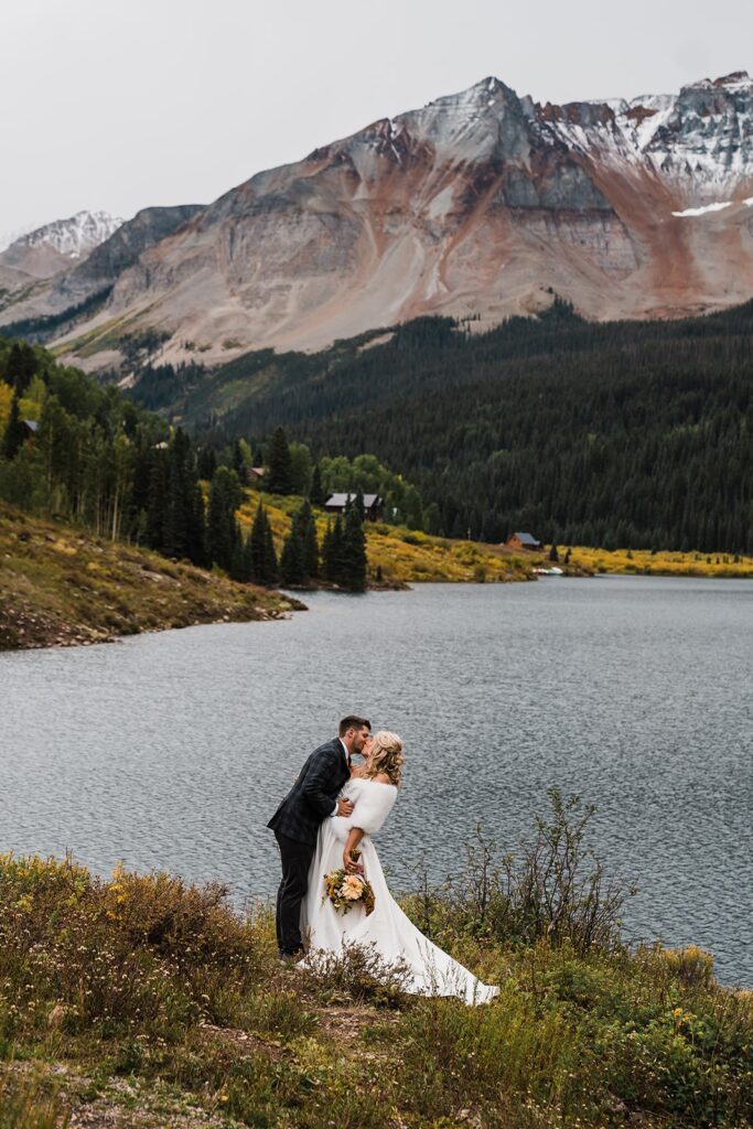 Bride and groom kiss by an alpine lake at their Telluride elopement