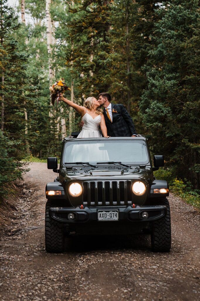 Bride and groom kiss while standing in a black Jeep at their elopement in the Colorado mountains