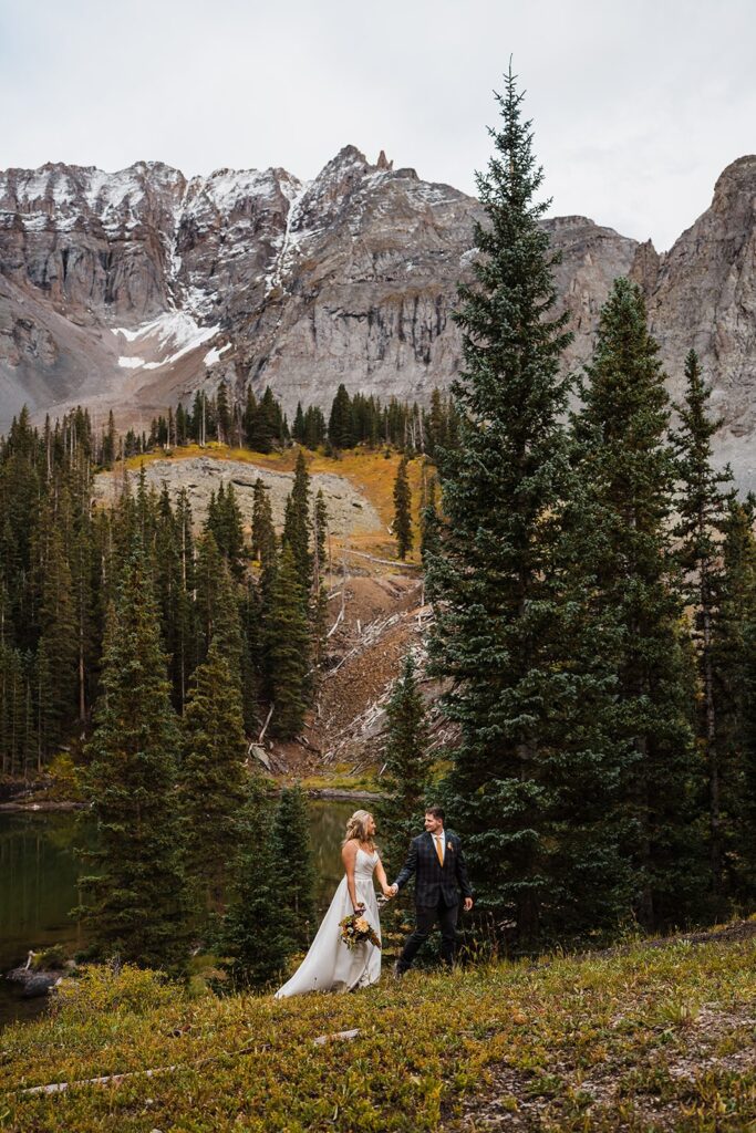 Bride and groom hold hands while walking through the mountains during their Telluride elopement