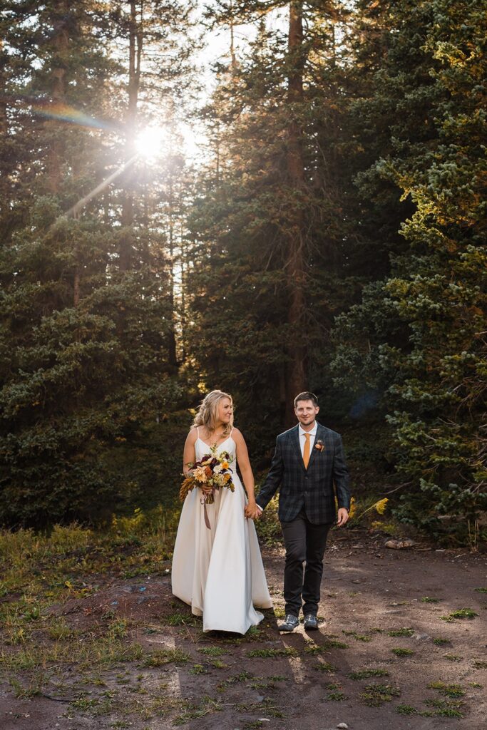 Bride and groom hold hands while walking through a hiking trail at their Telluride elopement
