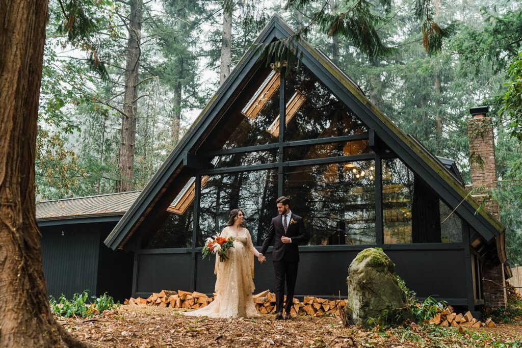 Bride and groom hold hands in front of their Airbnb cabin in Washington