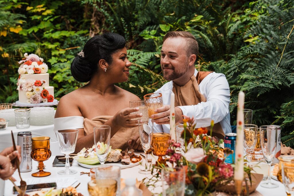 Bride and groom toast each other during their wedding reception at an Airbnb cabin
