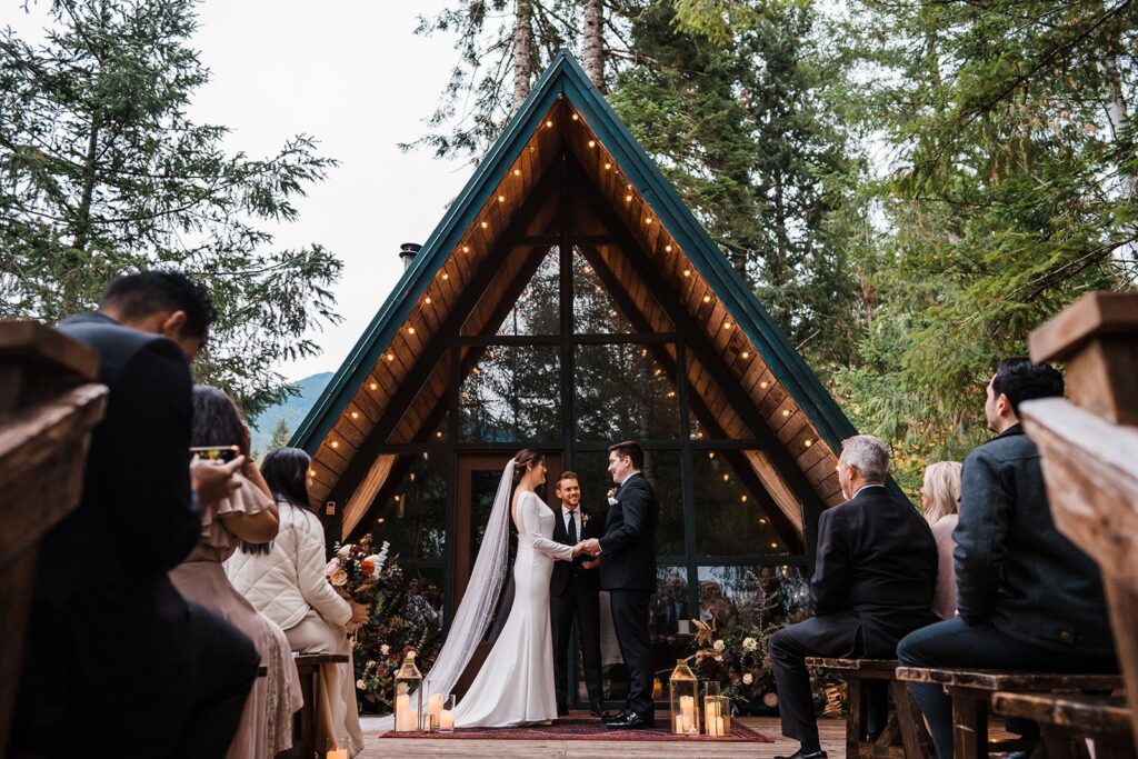 Bride and groom hold hands during their Airbnb wedding ceremony at an A-frame cabin