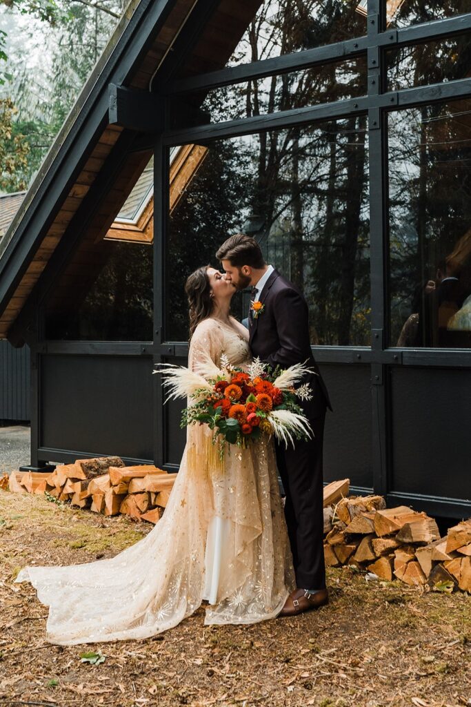 Bride and groom kiss during their first look at their Airbnb wedding cabin
