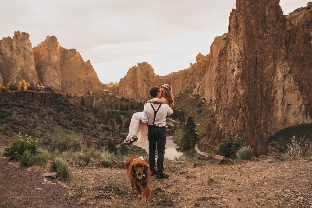 Groom carries bride across Smith Rock State Park while they elope in Oregon