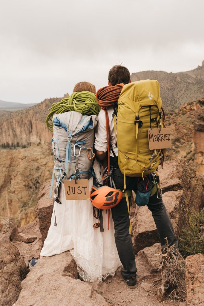 Bride and groom wear hiking backpacks during their desert elopement in Oregon