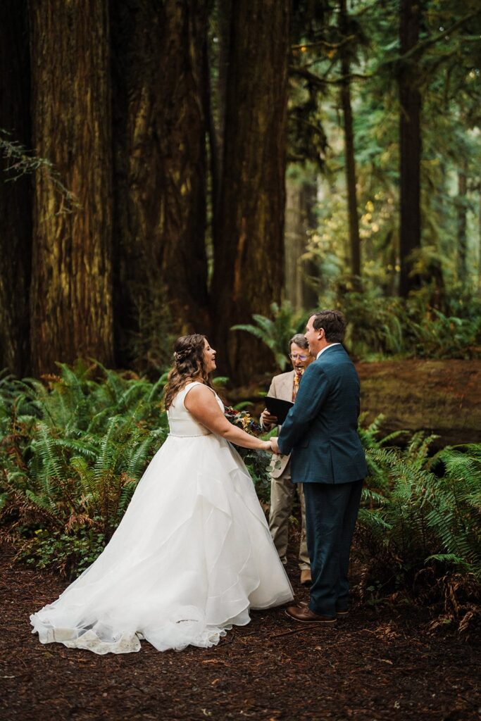 Bride and groom hold hands while they elope in the forest in Oregon