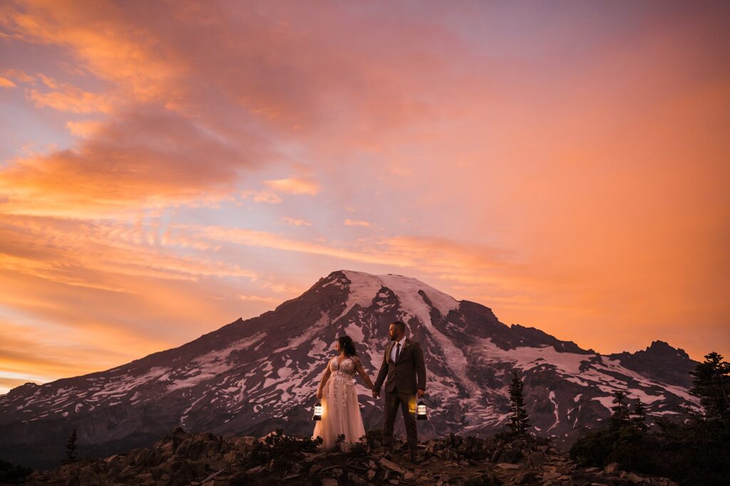 Bride and groom hold hands in front of Mt Rainier during alpenglow