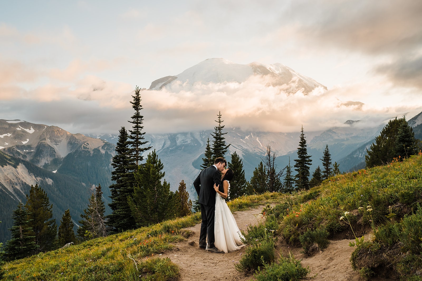 Bride and groom kiss on a mountain trail during their Washington elopement 