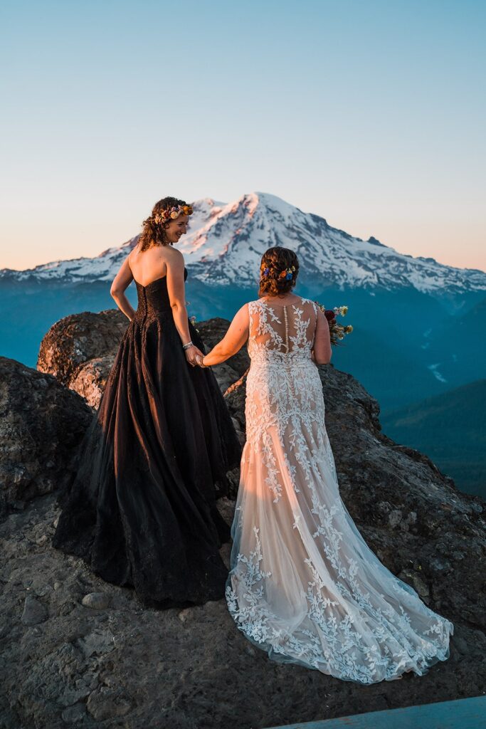 Brides hold hands while walking up an overlook at Mt Rainier National Park