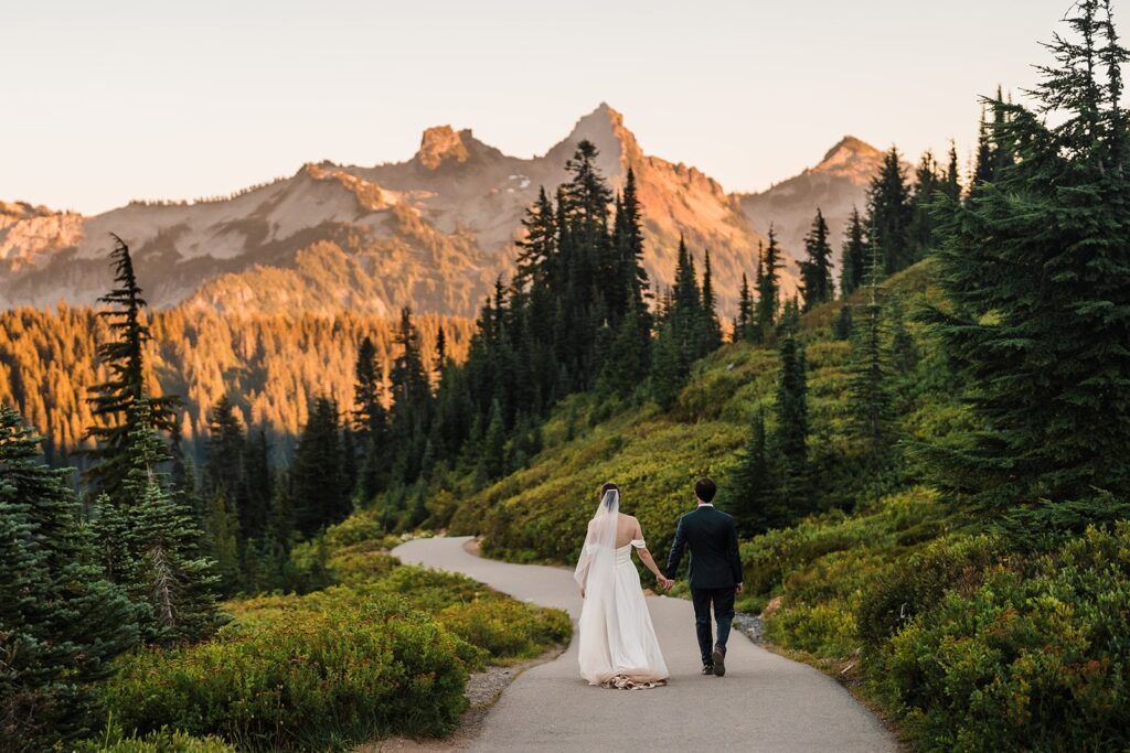 Bride and groom hold hands while walking along a trail during their Mt Rainier elopement