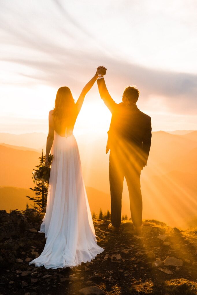 Bride and groom lift their hands into their air during their sunset elopement in Olympic National Park
