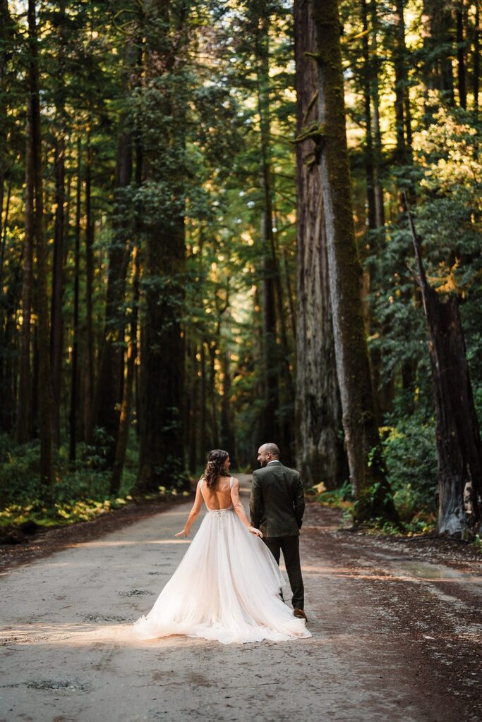 Bride and groom walk down a forest trail at their Redwood National Park elopement
