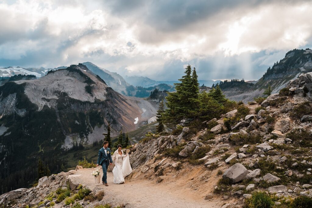 Bride and groom hold hands as they walk through a mountain trail at their Washington micro wedding 