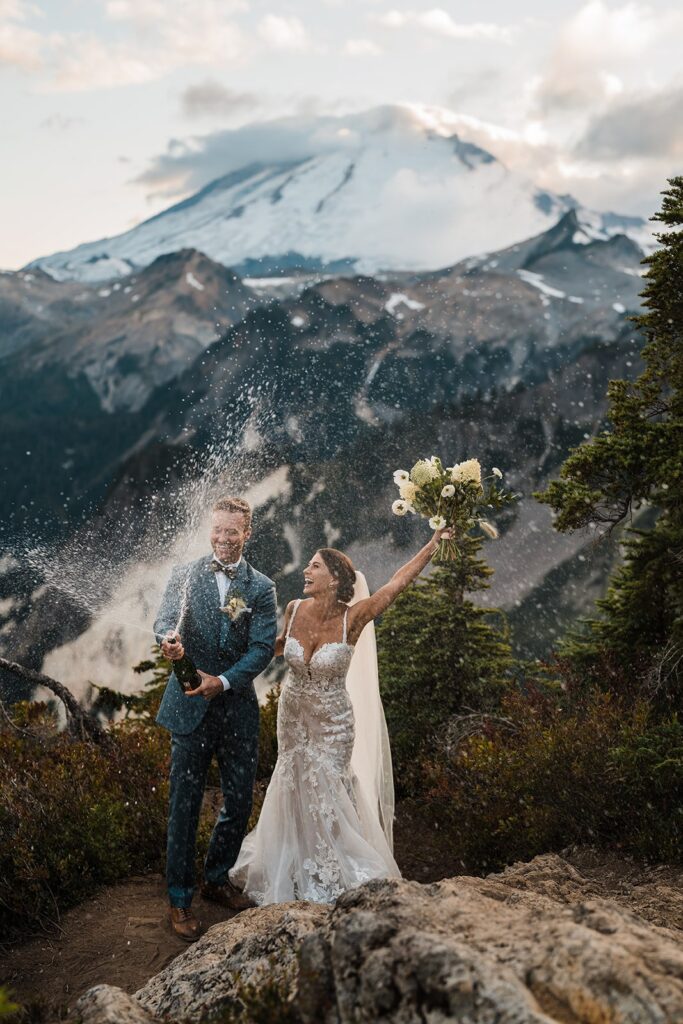 Bride and groom pop champagne and cheer during their Washington micro wedding photos in the mountains 