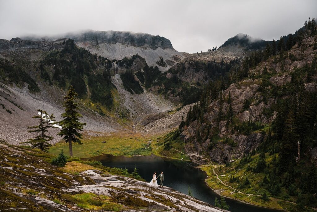 Bride and groom hold hands as they walk around a mountain trail at their North Cascades elopement