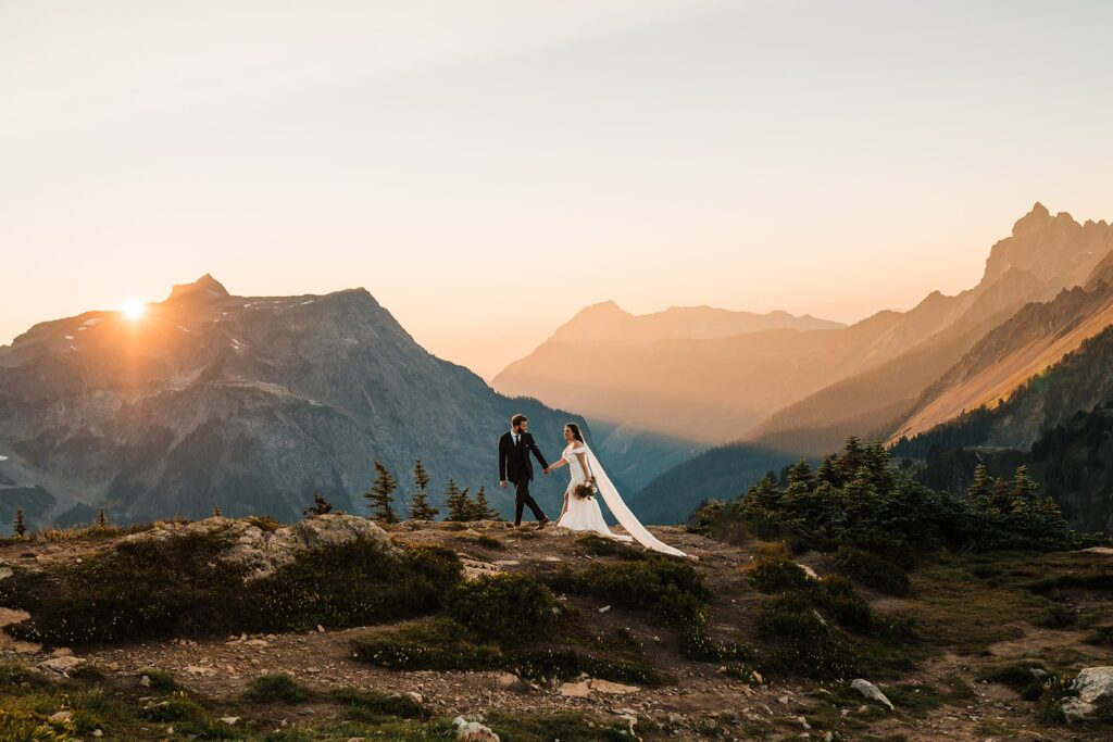 Bride and groom hold hands while walking through a mountain trail at their North Cascades National Park elopement