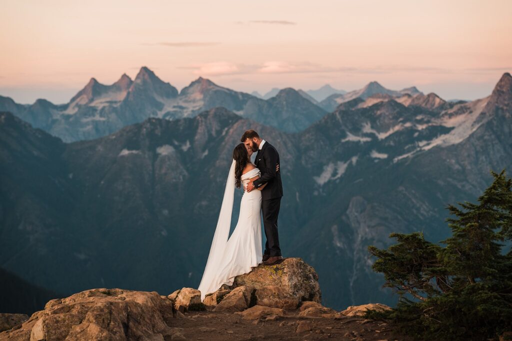 Bride and groom kiss on top of the mountains while they elope in Washington