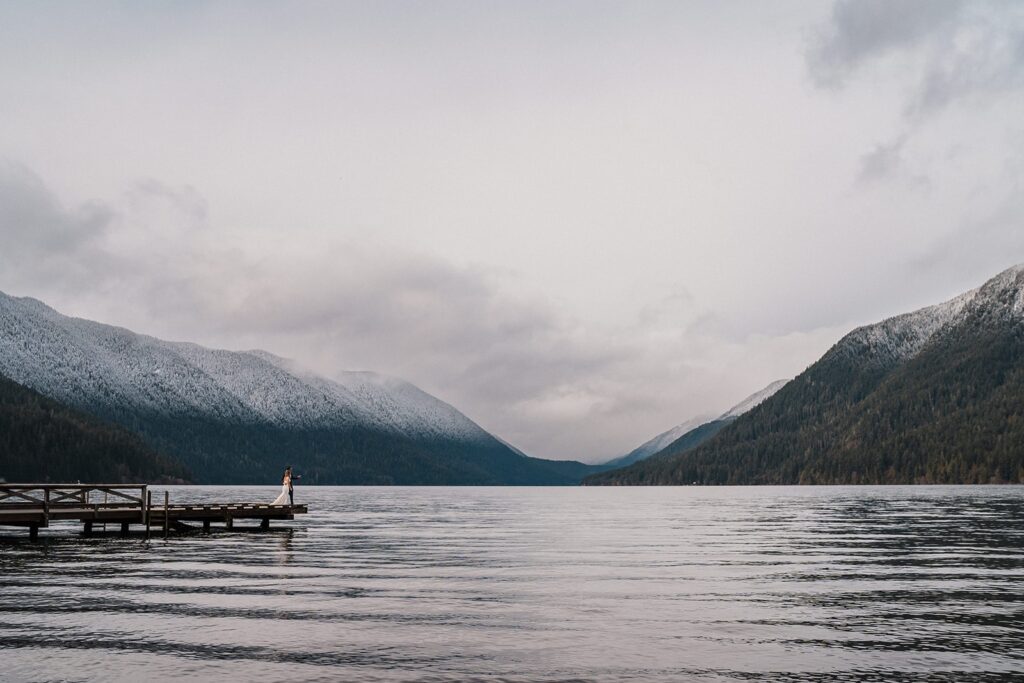 Bride and groom stand on a dock at their lake elopement in Olympic National Park