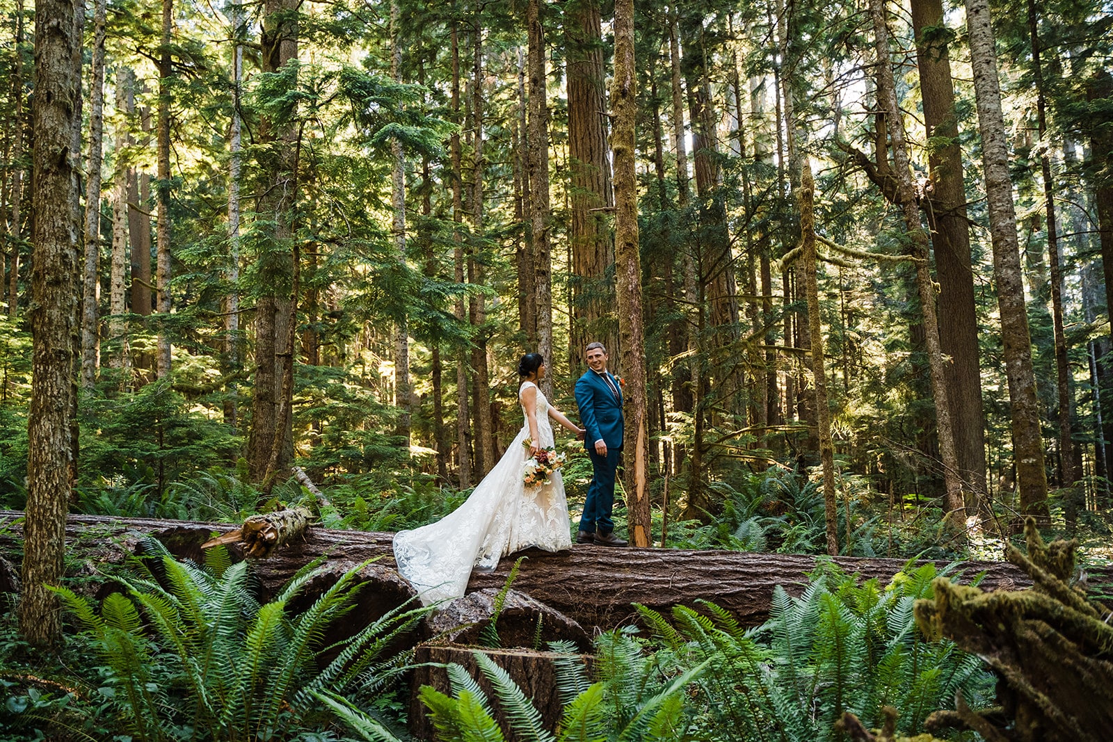 Bride and groom stand on a fallen tree in the Hoh Rainforest during their elopement in Washington