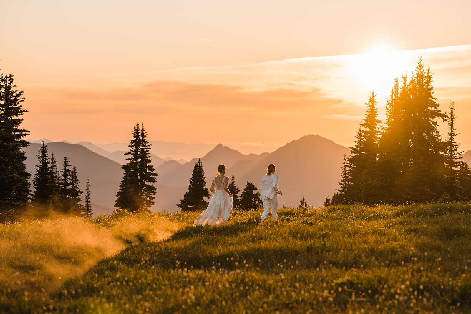 Two brides run across a trail at their national park wedding on the Olympic Peninsula